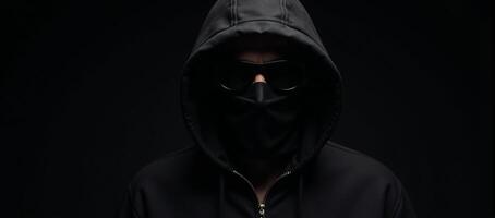 Dramatic portrait of a shadowyhooded bank robber on a dark backdrop photo
