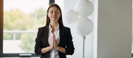Portrait of an adult businesswoman meditating with closed eyes and Namaste pose in natural light against blurry orbs photo