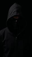 Dramatic portrait of a shadowyhooded bank robber on a dark backdrop photo