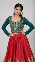 A traditionallydressed woman sporting an ornate goldembroidered teal top with a red skirt photo