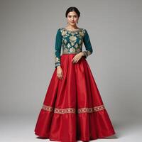 A traditionallydressed woman sporting an ornate goldembroidered teal top with a red skirt photo
