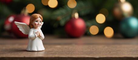 A cute little Christmas Angel is perched upon a wooden table with festive backdrop of blurred Christmas decorations photo