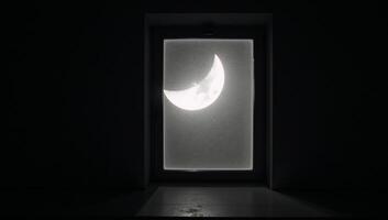 A halfmoon illuminates a dark room from an open window at night photo