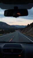 View from a cars rearview mirror featuring the road stretching out behind photo