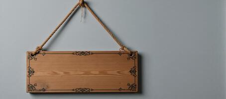 Antique wooden sign with rope detail hanging against grey wall photo