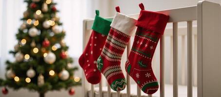 Cozy nursery scene features three Christmas stockings hanging from a crib with a soft glow from a nearby Christmas tree photo