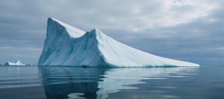A floating iceberg mirrors its image in the tranquil waters below it photo