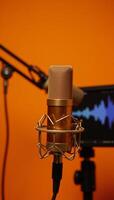 Golden mic and pop filter set up against sound waves on vivid orange backdrop professional recording setup photo