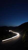 A twilight road with headlightlit curves set amidst a starry night sky photo