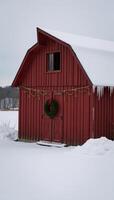 Rustic barn adorned with Christmas wreath lit up on a snowy field during wintertime photo