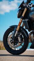 Detailed closeup image of shiny motorcycle wheel with intricate front suspension beneath a clear blue sky photo