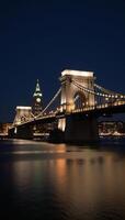 Cityscape featuring iconic bridge at night with shimmering reflections photo