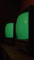Dark room featuring vintage TV sets with emeraldhued screens photo