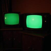 Dark room featuring vintage TV sets with emeraldhued screens photo