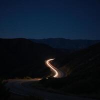 A twilight road with headlightlit curves set amidst a starry night sky photo