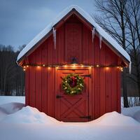 Rustic barn adorned with Christmas wreath lit up on a snowy field during wintertime photo