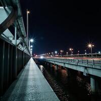 A litup city bridge showcases the glow from passing vehicles crossing during nighttime photo