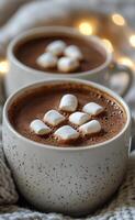 Warm hot chocolate topped with marshmallows beside cozy lights in a winter setting photo