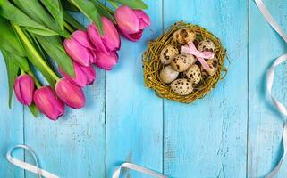 Spring background. Bouquet of flowers on a wooden background and a nest with eggs. spring photo