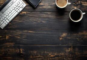 A wooden desk setup featuring a keyboard, cup of coffee, and a notepad in a cozy workspace photo