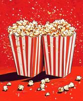 Crunchy popcorn in striped boxes arranged on a vibrant red background with scattered pieces photo