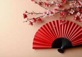 Elegant red folding fan accompanied by blossoming cherry branches on a soft background photo