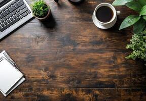 A wooden desk setup featuring a keyboard, cup of coffee, and a notepad in a cozy workspace photo
