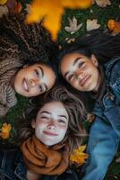 Three friends enjoying autumn leaves while lying together on the grass in a park setting photo