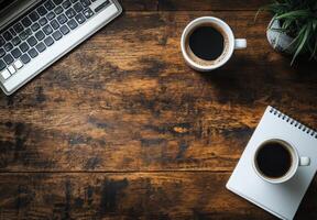 A wooden desk setup featuring a keyboard, cup of coffee, and a notepad in a cozy workspace photo