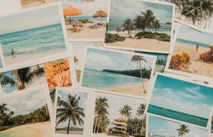 Vintage travel photographs of tropical beaches and palm trees scattered on a wooden surface photo