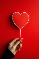 A hand holding a heart shaped card against a red background during a creative arts session photo