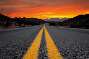 The winding road leading to a vibrant sunset over the mountains in the desert landscape photo