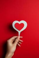 A hand holding a heart shaped card against a red background during a creative arts session photo
