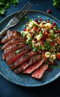 Grilled steak slices served with pomegranate quinoa salad on a blue plate photo