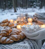 Cozy winter picnic with croissants and marshmallows in a snowy forest setting at dusk photo
