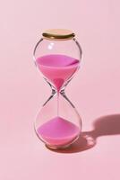 Elegant hourglass with pink sand on a vibrant pink backdrop, emphasizing the passage of time photo