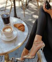 Relaxing in a cafe with a smartphone, coffee, and croissant during a sunny afternoon photo