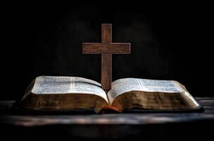 A wooden cross stands on an open Bible in a dimly lit room during evening hours photo