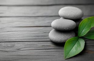 Relaxing stack of smooth stones with a green leaf on a wooden surface for wellness aesthetics photo