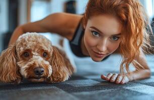 Young woman exercising on a mat at home while playfully interacting with her dog photo