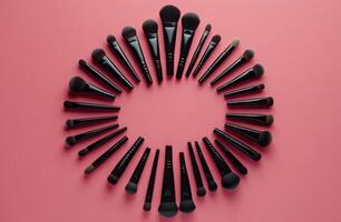 A colorful arrangement of makeup brushes and sponges on a vibrant pink background photo