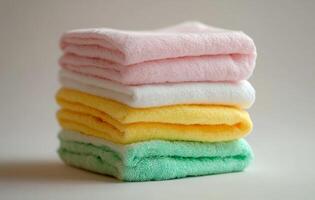 Neatly stacked colorful towels on a table in a bright, sunlit room during daytime photo