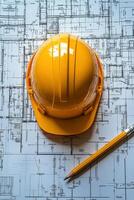 Yellow safety helmet rests on blueprints with a pencil on a construction table photo