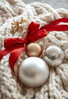 Cozy holiday decorations of silver and gold ornaments on a knitted blanket with warm lights photo
