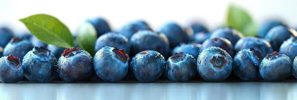 Freshly harvested blueberries with green leaves arranged on a white background photo