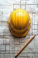 Yellow safety helmet rests on blueprints with a pencil on a construction table photo