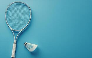 A badminton racket and shuttlecock resting on a blue background, ideal for sports enthusiasts photo