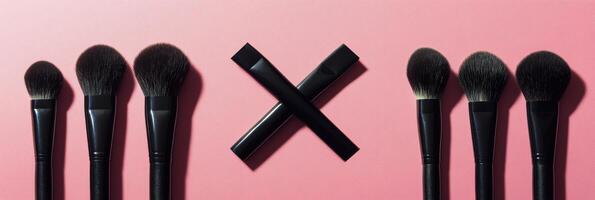 A set of makeup brushes in varying shapes on a pink background photo
