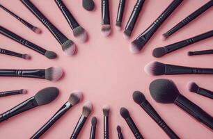 A colorful arrangement of makeup brushes and sponges on a vibrant pink background photo