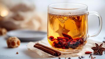 Warm herbal tea with goji berries and spices served in a glass cup on a winter day photo